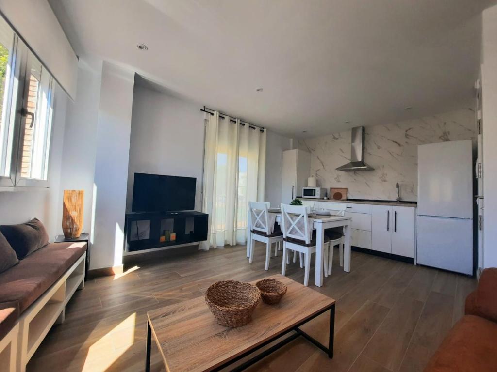 ein Wohnzimmer mit einem Sofa und einem Tisch sowie eine Küche in der Unterkunft Vive el Renacimiento: Ochío in Baeza