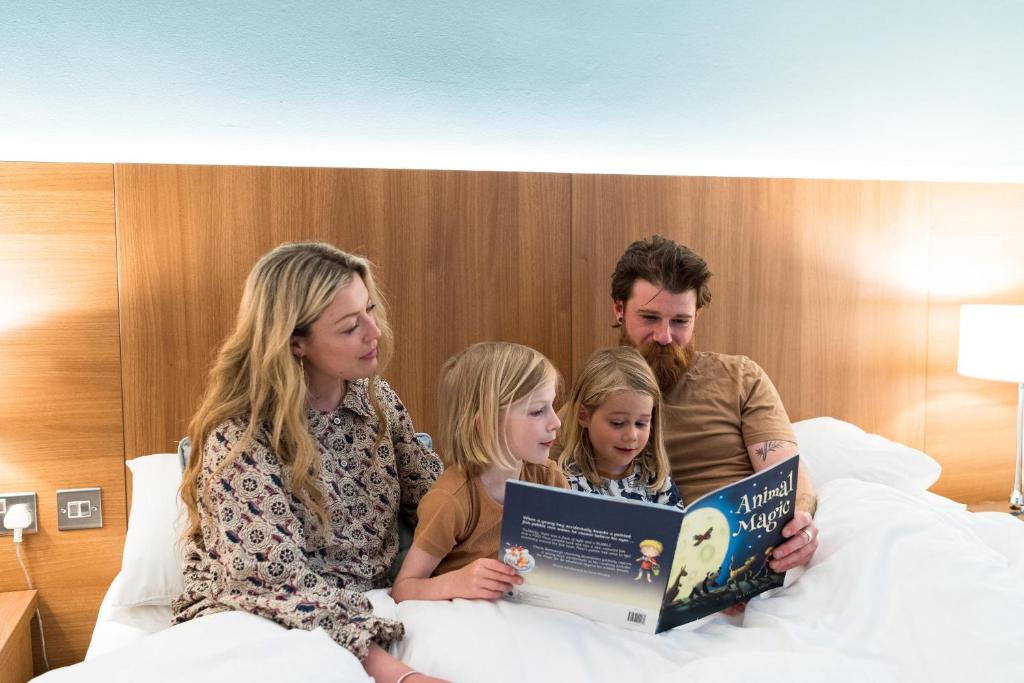 a family sitting in bed reading a book at Esplanade Hotel in Newquay