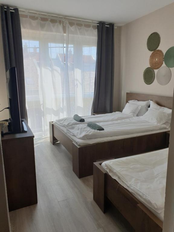 a bedroom with two beds and a tv and a window at Chill House Apartman Eger in Eger