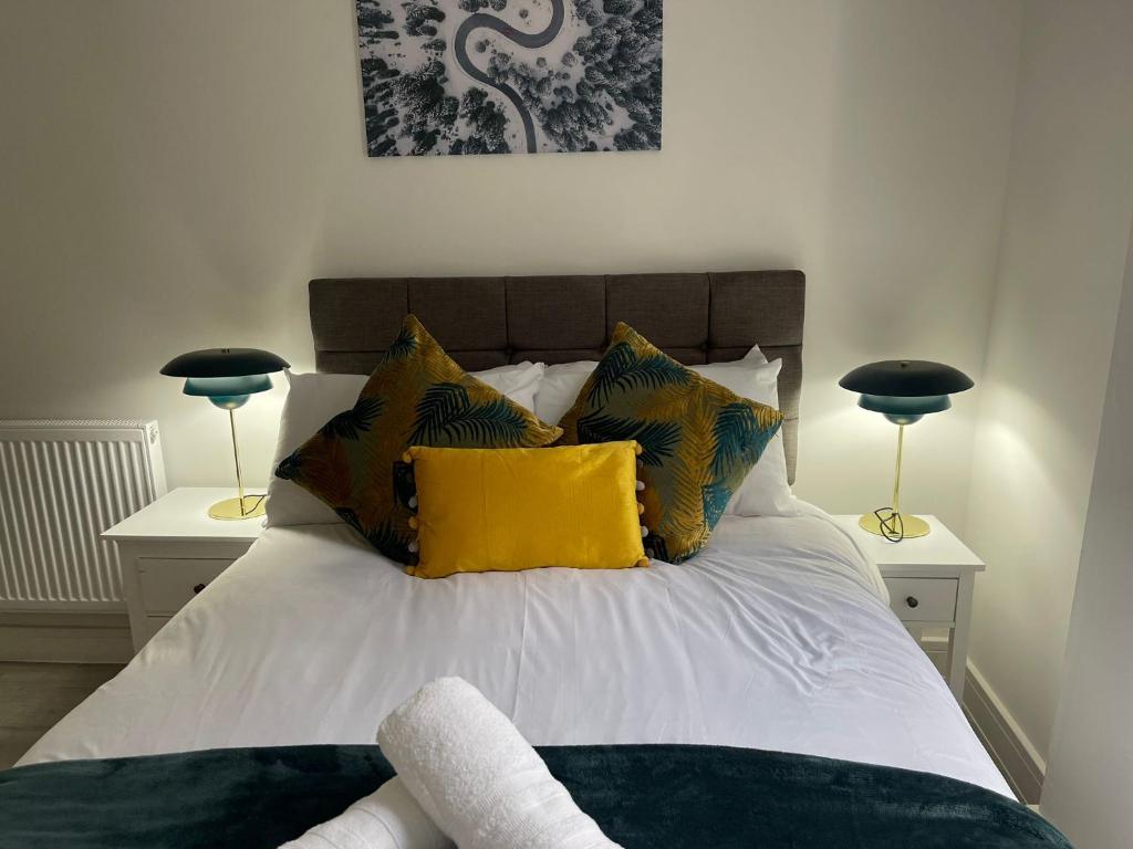 a bedroom with a bed with yellow pillows and two lamps at Kingdom apartments in Wolverhampton