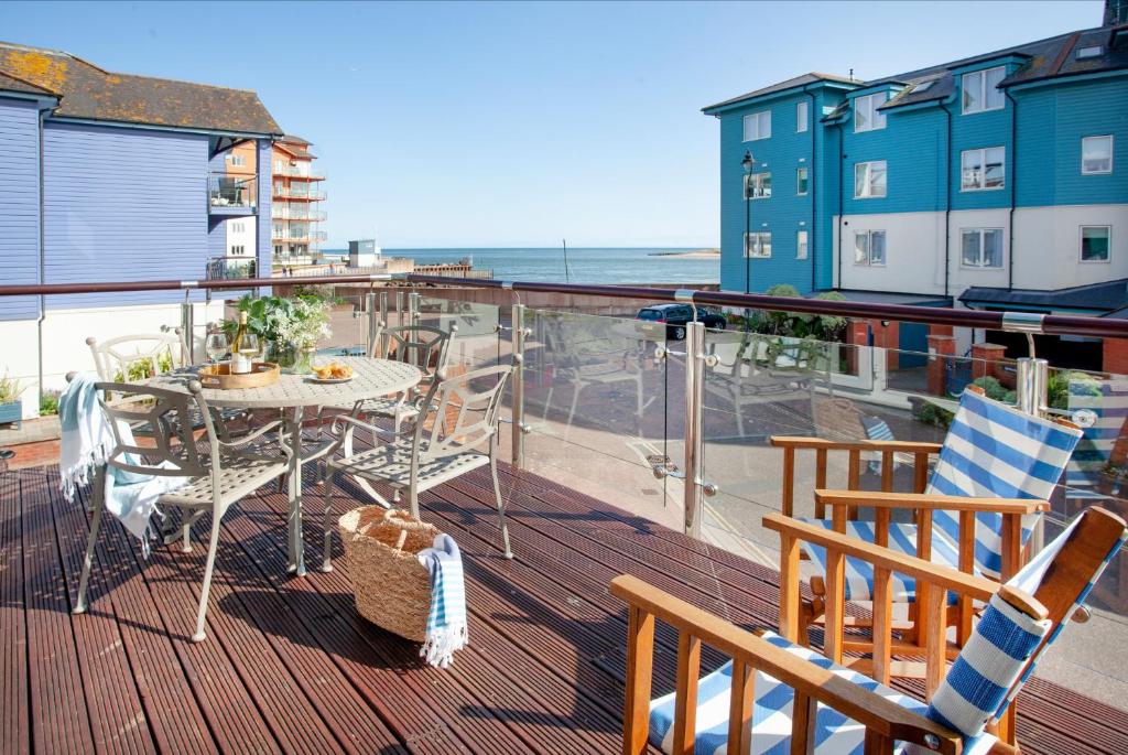 a balcony with a table and chairs and the ocean at Beacon House in Exmouth