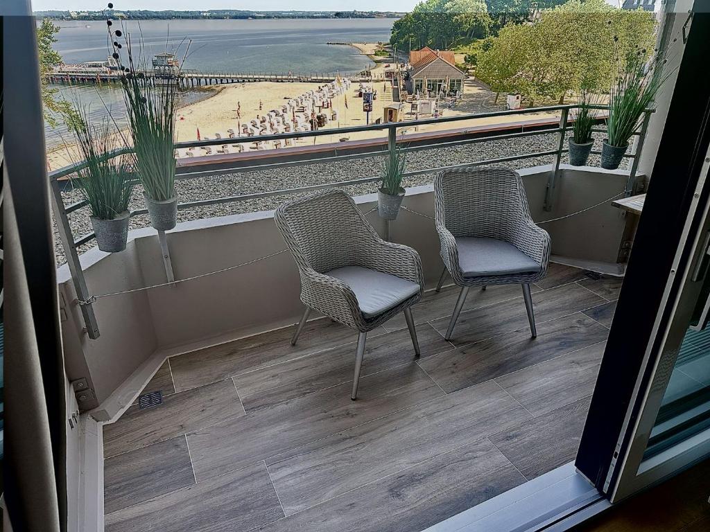 a balcony with two chairs and a view of the train tracks at fewo1846 Intermar - Kajuete Foerdeblick - familienfreundliches Studioapartment mit Balkon und Meerblick in Glücksburg