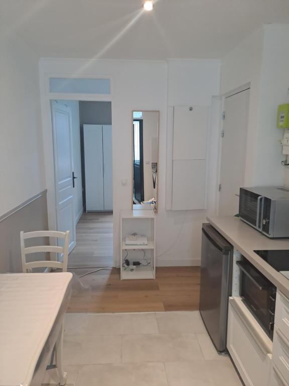 - une cuisine blanche avec une table et un four micro-ondes dans l'établissement Appartement tout confort Lumineux, à Paris