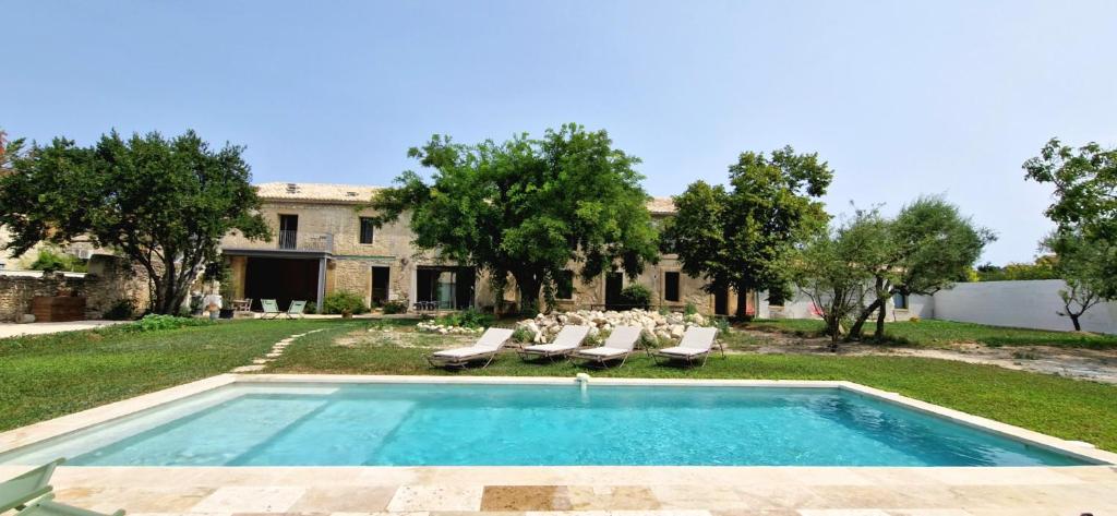 una piscina al aire libre con sillas y una casa en Appartement dans un mas provençal rénové en Saint-Hilaire-dʼOzilhan