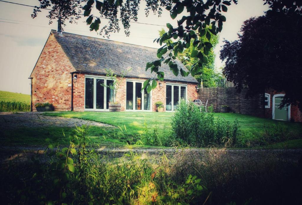 an old brick house with a grass yard in front of it at Cosy One Bed Barn Conversion Donington Park East Midlands Airport in Derby