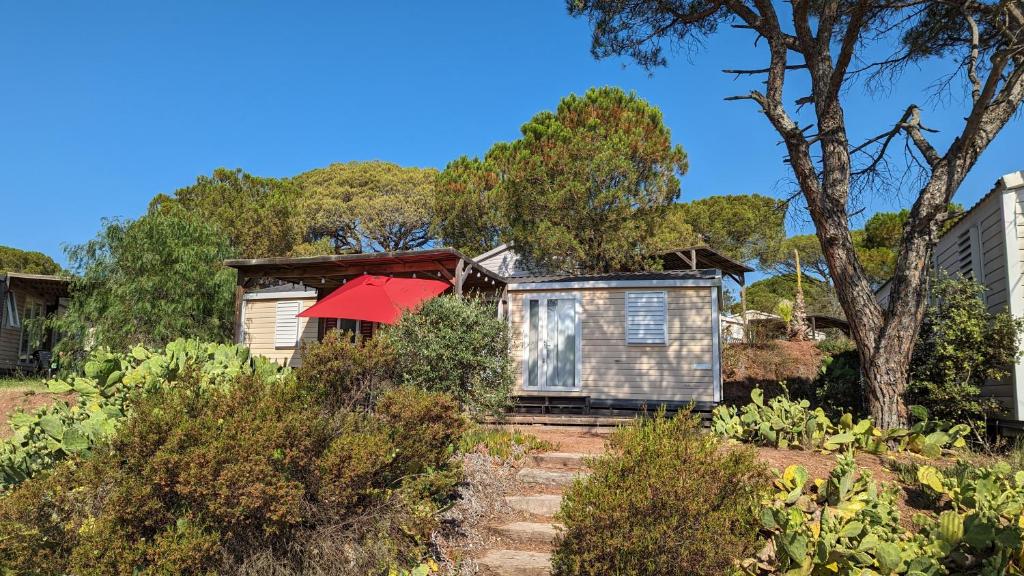 une maison avec un parasol rouge dans un jardin dans l'établissement MOBILOCAMP, au Muy