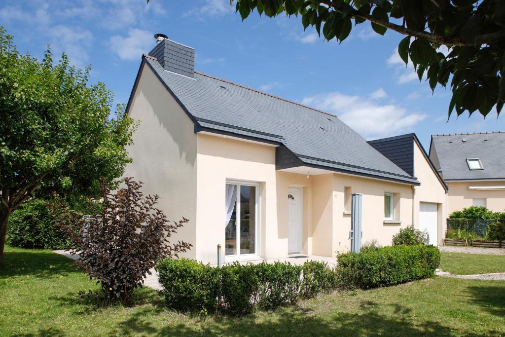 a white house with a black roof at La Charline - Maison avec jardin près de la plage in Frehel