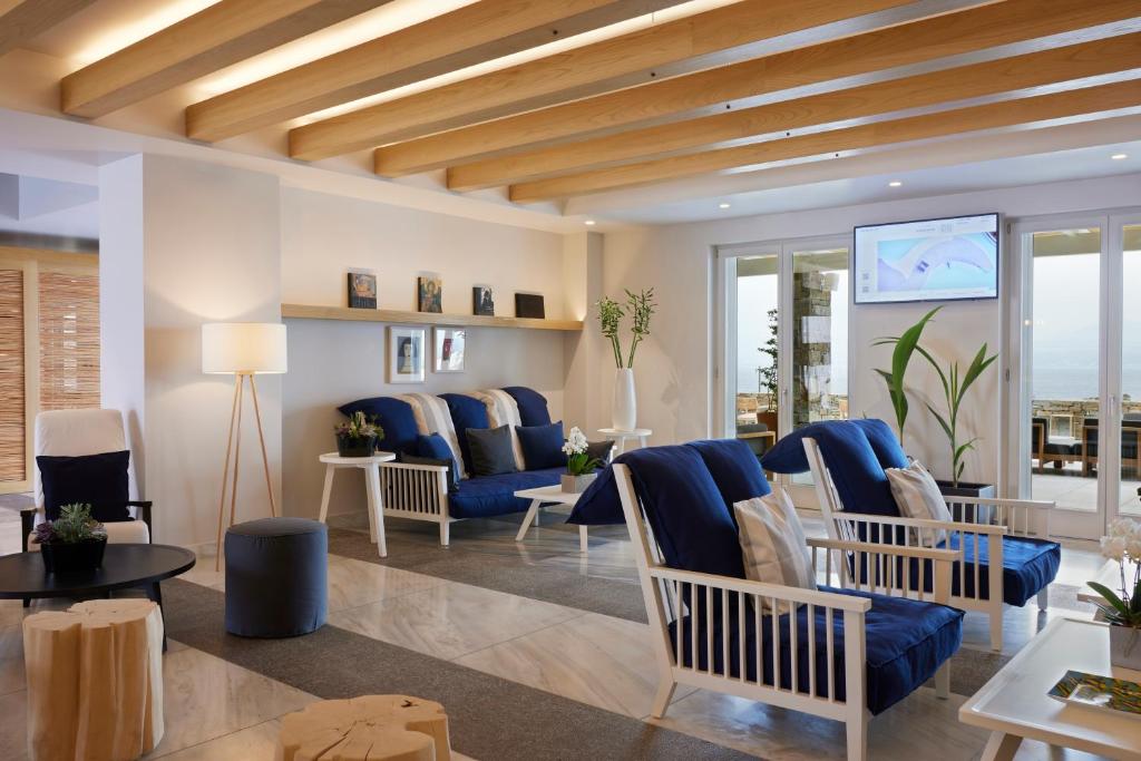 a living room with blue chairs and tables and windows at Summer Senses Luxury Resort in Logaras