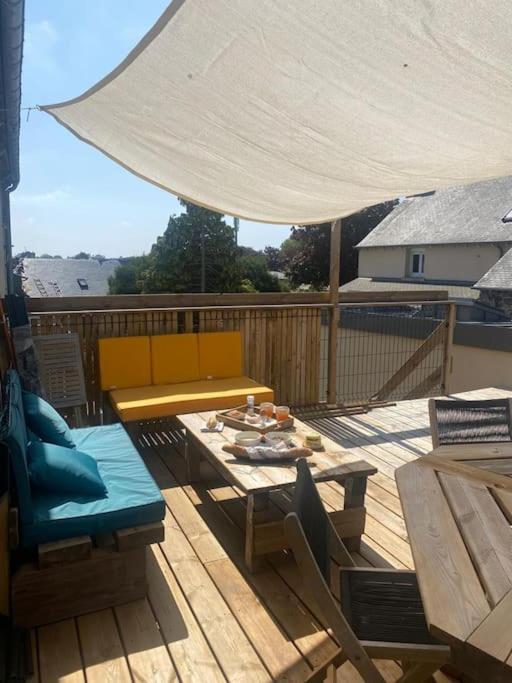 une terrasse en bois avec une table et un parasol blanc dans l'établissement Maison de ville - terrasse sud, a 10 min des plages, à Saint-Brieuc