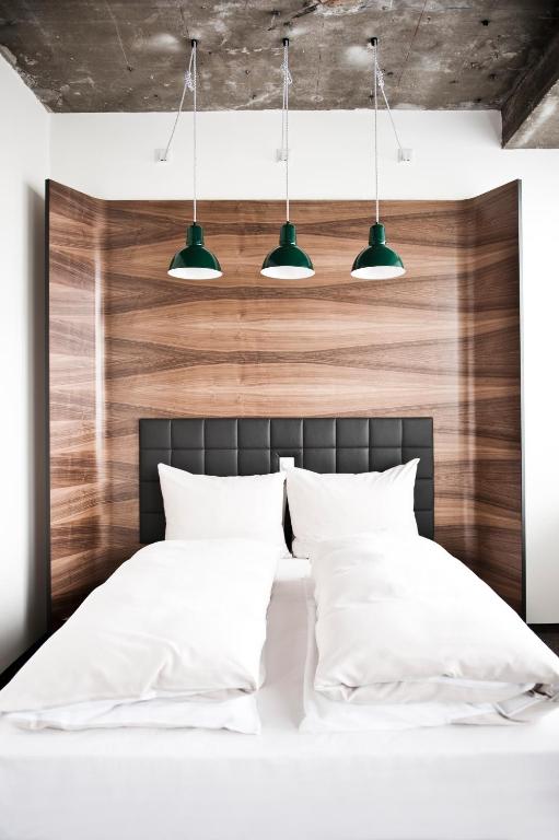 a bedroom with white pillows and a wooden headboard at Hotel Daniel Vienna - Smart Lifestyle Near City Centre in Vienna
