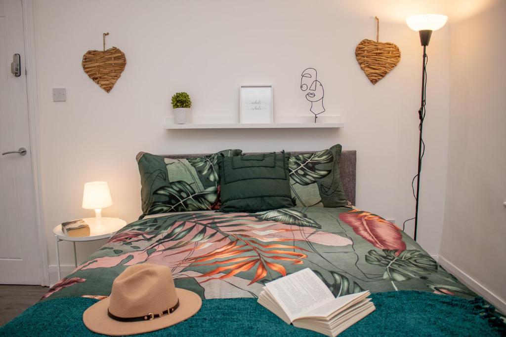 a bed with a hat and a book on it at Warm and relaxing hideaway in Aintree