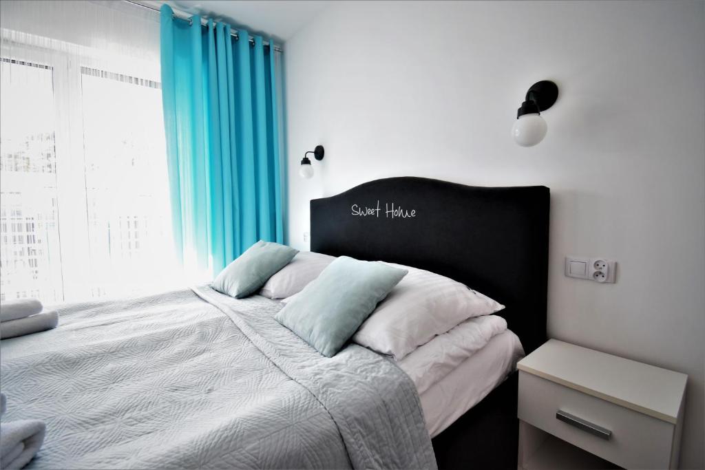 a bedroom with a large bed with blue curtains at Apartament Sweet Home Pogorzelica in Pogorzelica