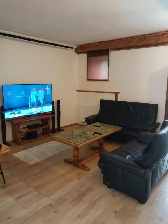 een woonkamer met een bank, een tafel en een tv bij Wczasy Żywki in Kruklanki