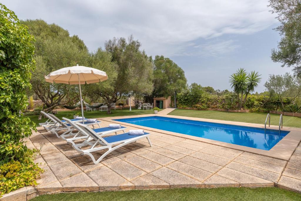 einen Pool mit 2 Liegestühlen und einem Sonnenschirm in der Unterkunft Villa sa teulada in Santa Margalida