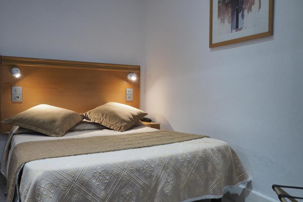 1 dormitorio con 1 cama grande y cabecero de madera en Hotel Busby, en Niza