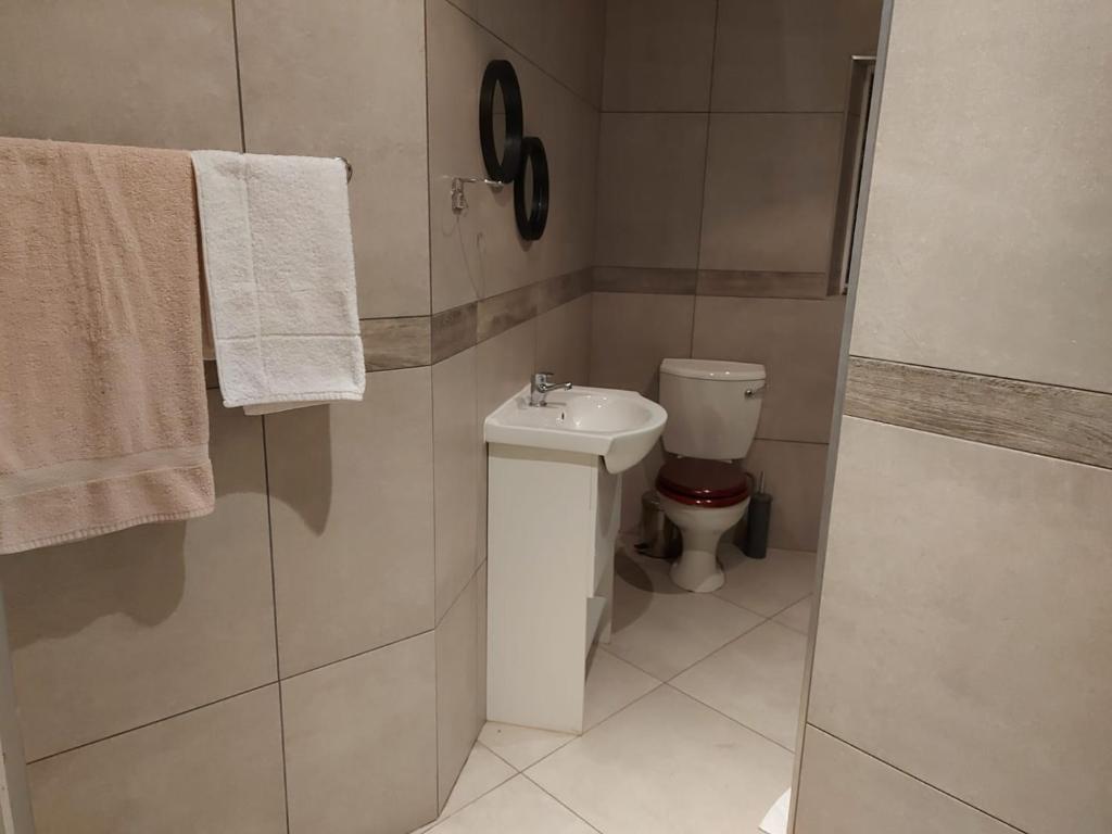 a bathroom with a toilet and a sink and towels at KLOOFIES GUESTHOUSE in Roodepoort
