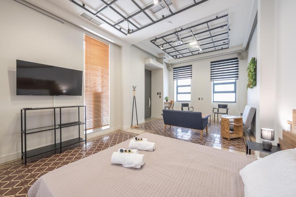 een kamer met een bed, een tv en een bank bij Artistic spacious home at Gazi in Athene