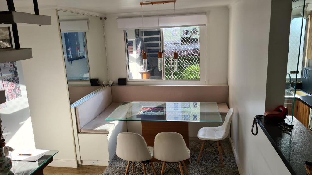 a small kitchen with a glass table and white chairs at Condomínio Olhos D'agua in Mauá