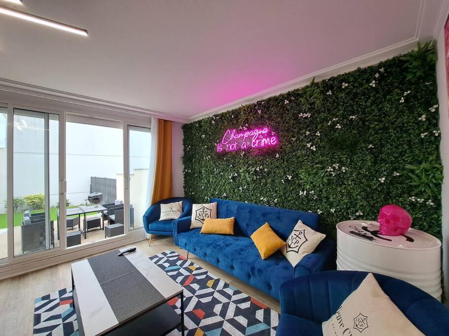 uma sala de estar com um sofá azul e uma parede verde em Camden - Extérieur et parking em Reims
