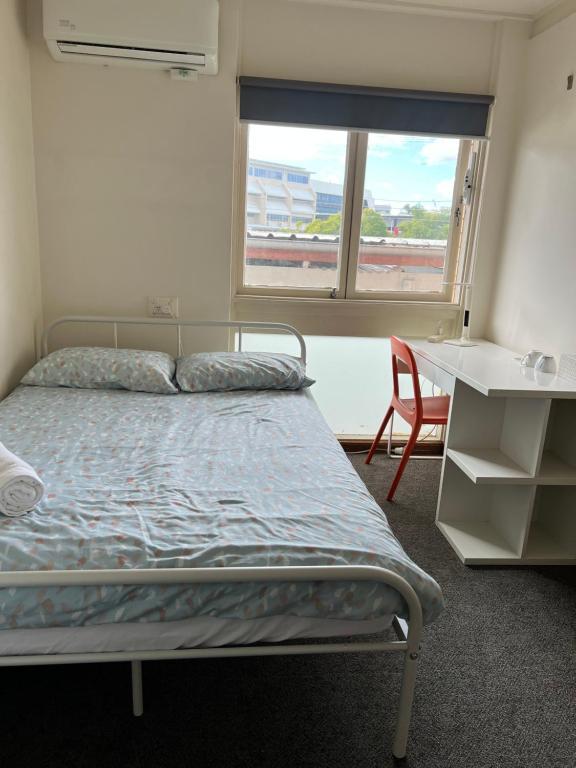 een slaapkamer met een bed, een bureau en een raam bij Adalong Student Guest House in Brisbane