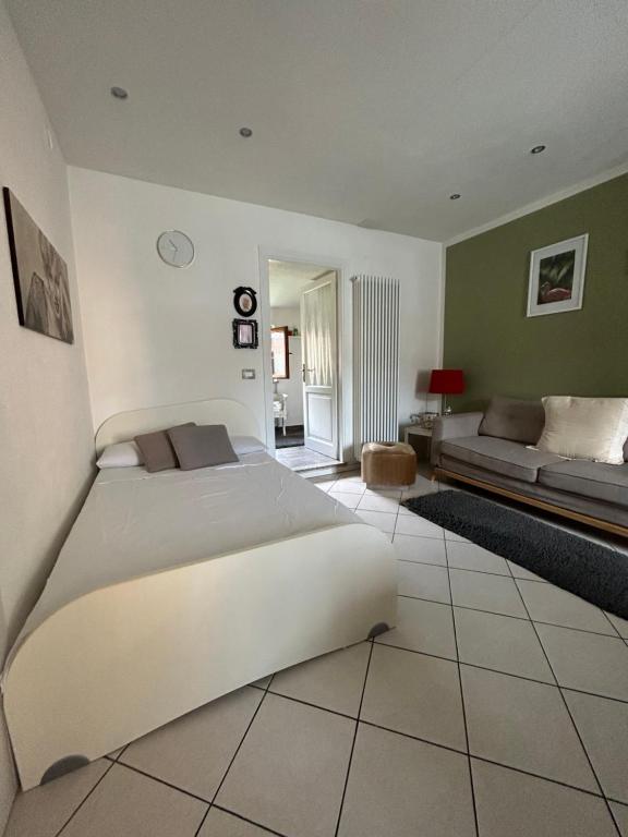 1 dormitorio con 1 cama blanca grande y 1 sofá en LA TANA Guest House en Dronero