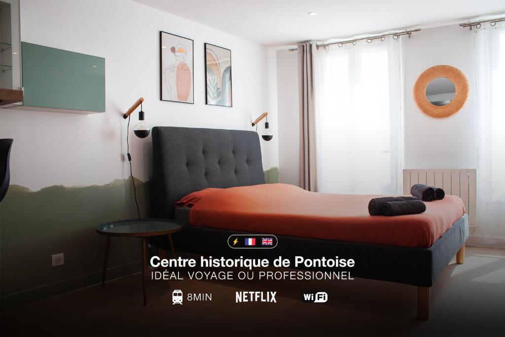 1 dormitorio con 1 cama y 1 mesa en una habitación en Studio cosy en plein cœur historique de Pontoise, en Pontoise