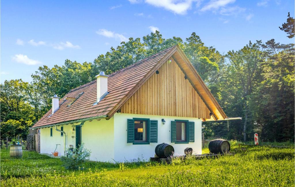 ein kleines weißes Haus mit einem Holzdach und zwei Weinfässern in der Unterkunft Kellerstoeckl In Strem in Strem