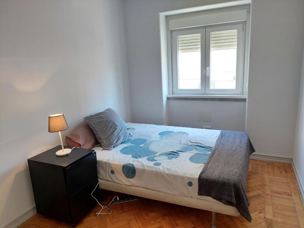 1 dormitorio con 1 cama con lámpara y ventana en Amoreira Room, en Lisboa