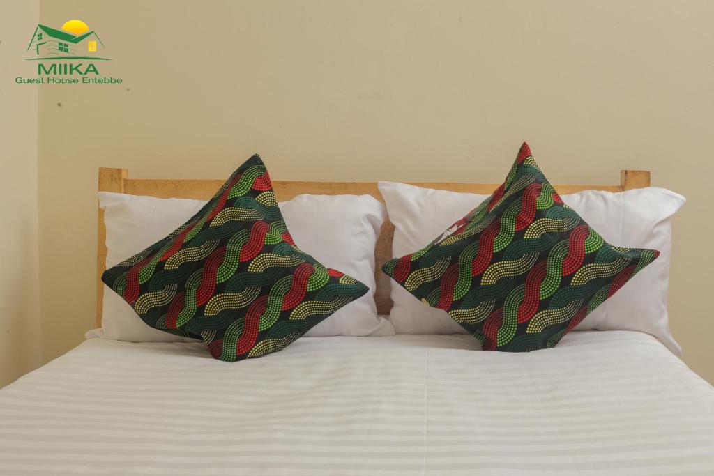 2 almohadas sentadas encima de una cama en Miika Guest House en Entebbe
