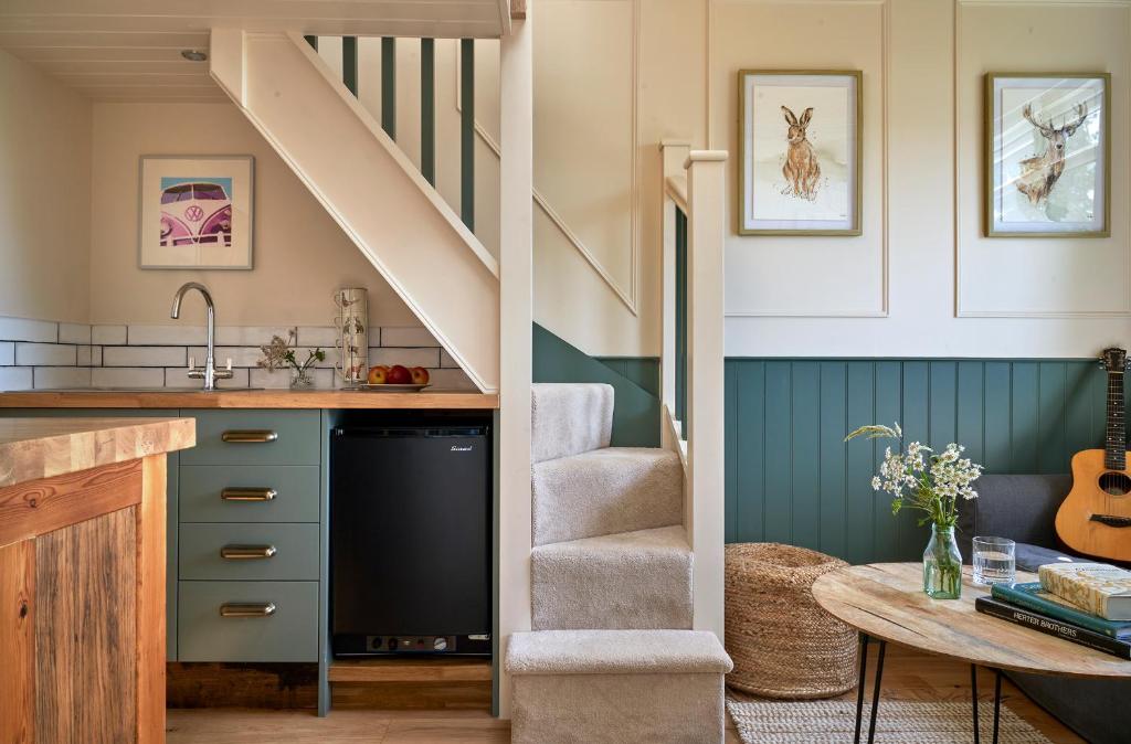 a kitchen with a staircase and a sink and a table at Extraordinary Huts Ltd in Rye