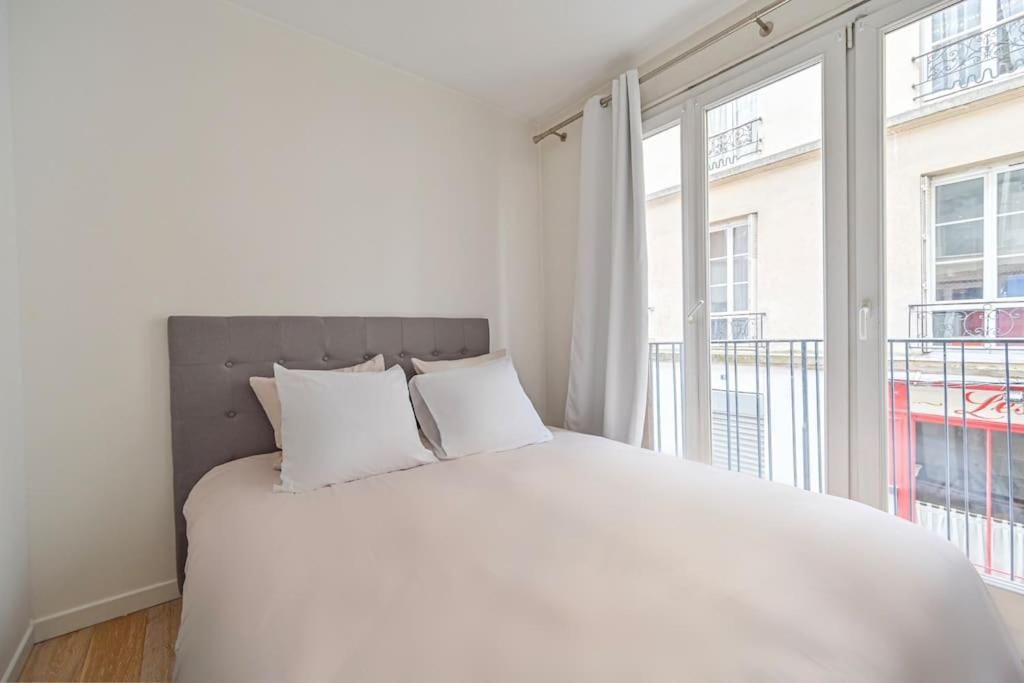 - une chambre avec un grand lit blanc et une grande fenêtre dans l'établissement Warm & Welcoming Flat - Family's Ideal - Marais, à Paris