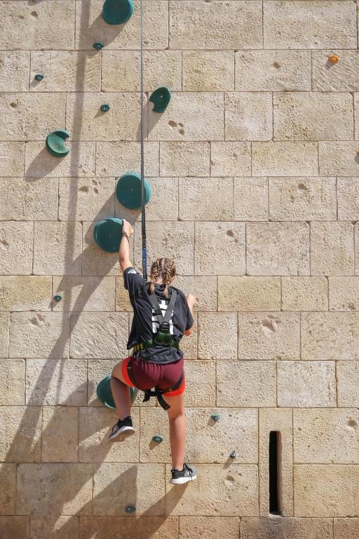 a woman is climbing on a rock wall at City of Dreams Mediterranean - Integrated Resort, Casino & Entertainment in Limassol