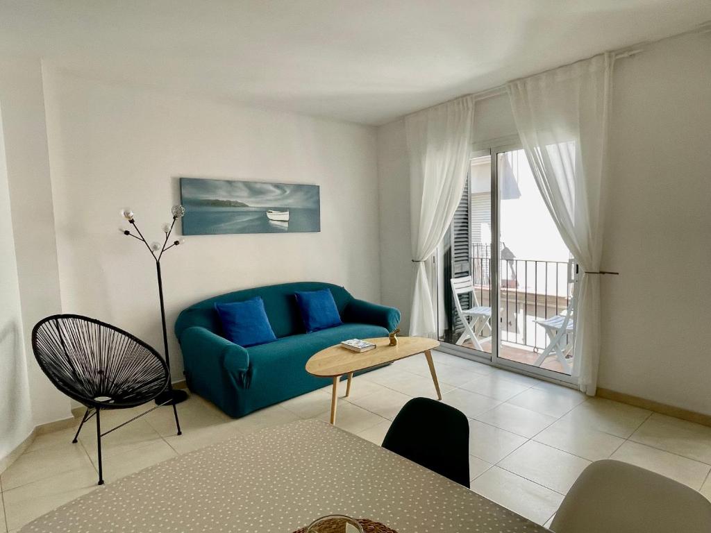 a living room with a blue couch and a balcony at Sant Pau Beach Home with terrace in Sitges