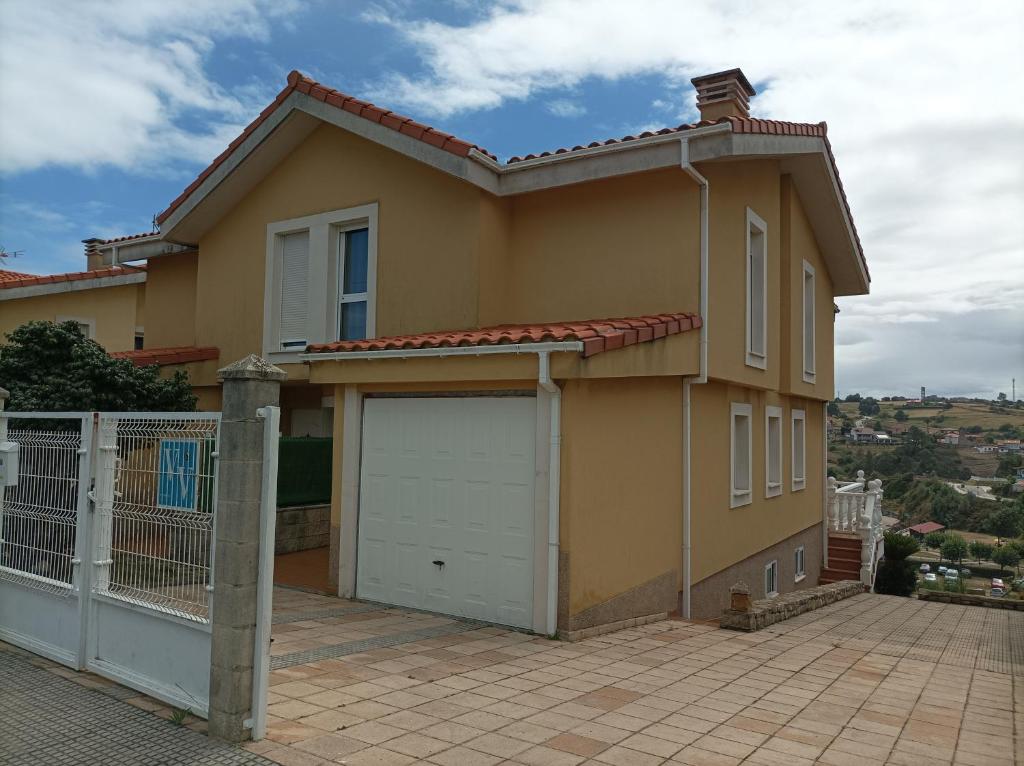 uma casa com duas portas de garagem e uma cerca em La Cariñosa em Naveces