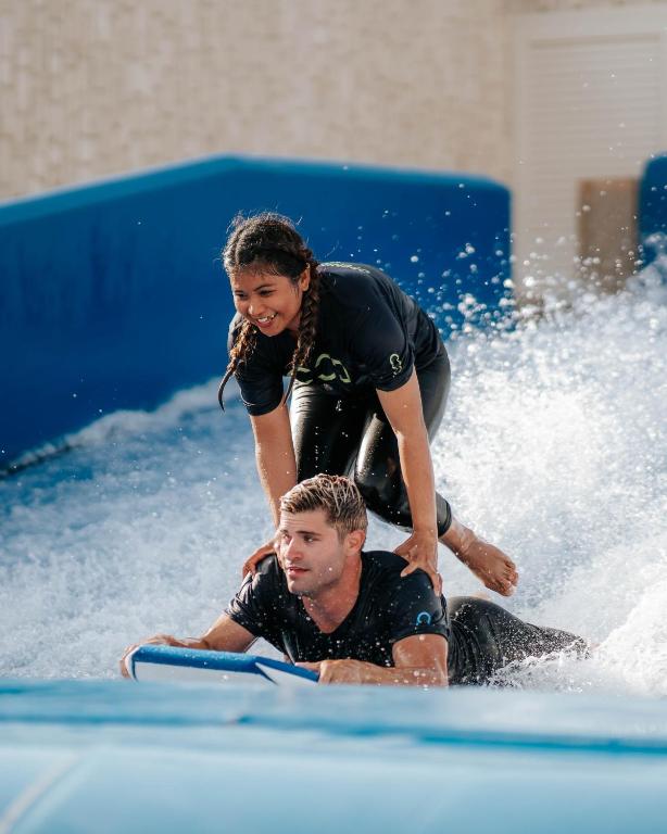 a woman helping a man on a surfboard in the water at City of Dreams Mediterranean - Integrated Resort, Casino & Entertainment in Limassol