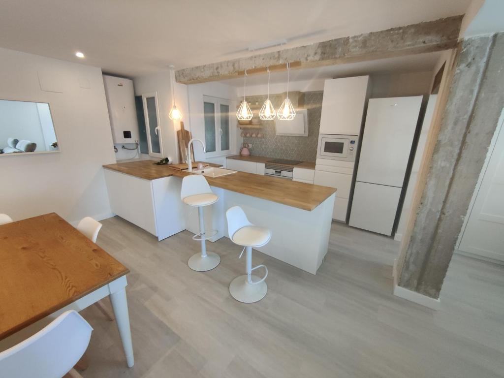 a kitchen with white cabinets and a counter with stools at Atractivo piso recién reformado in Santander