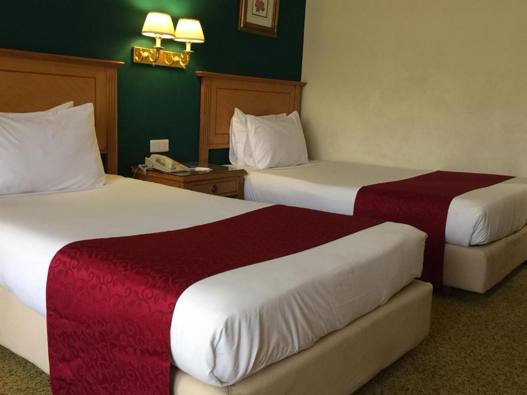 um quarto de hotel com duas camas com lençóis vermelhos e brancos em Amarante Pyramids Bed Room no Cairo