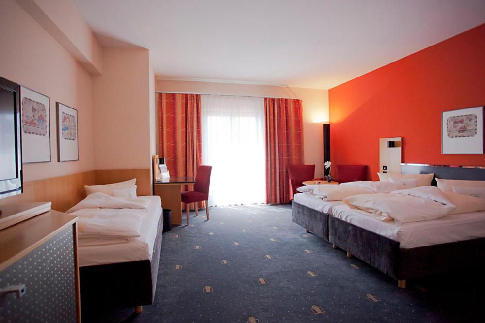 a hotel room with three beds and a window at Hotel Theresientor in Straubing