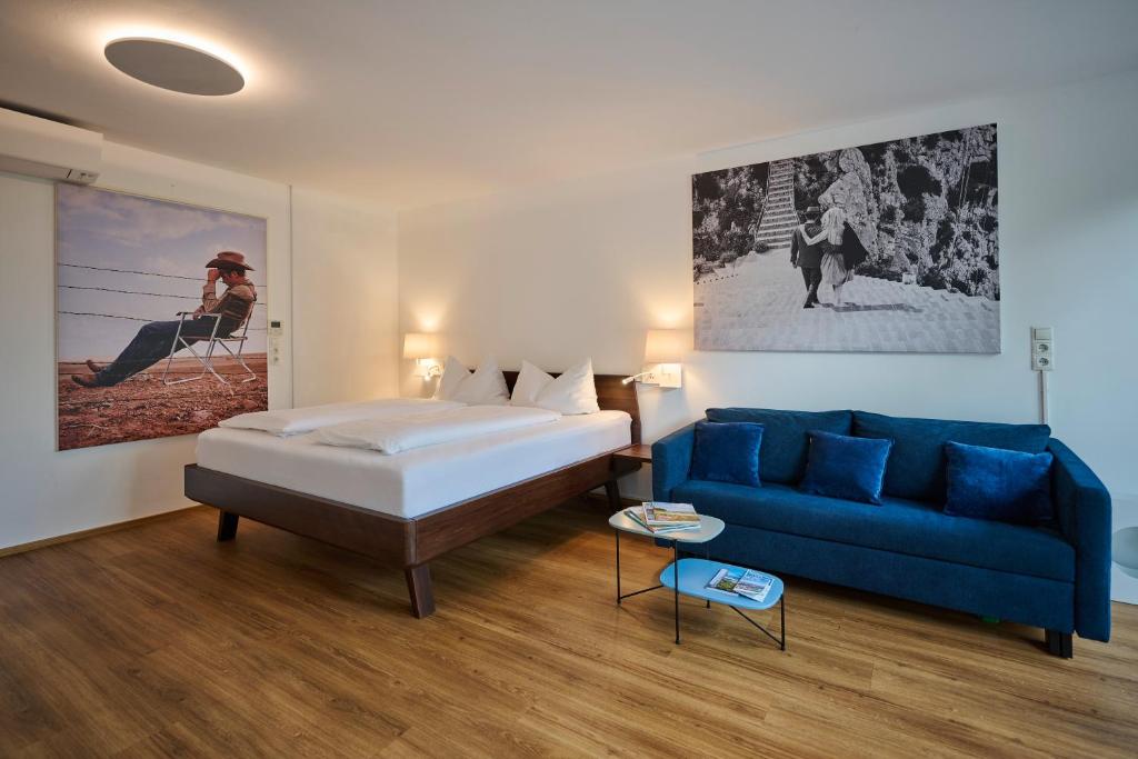 a bedroom with a bed and a blue couch at Charmantes Apartment im Grünen in Bregenz
