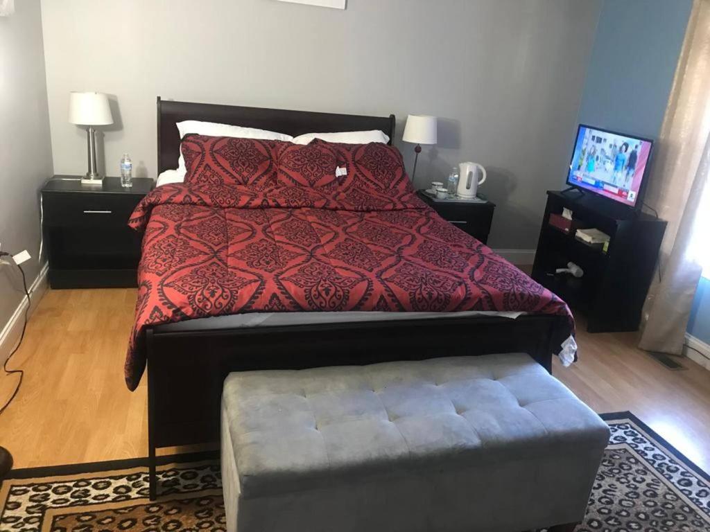 ein Bett mit einer roten Bettdecke und einem Hocker im Schlafzimmer in der Unterkunft Room in House - Executive Private Room in Alexandria
