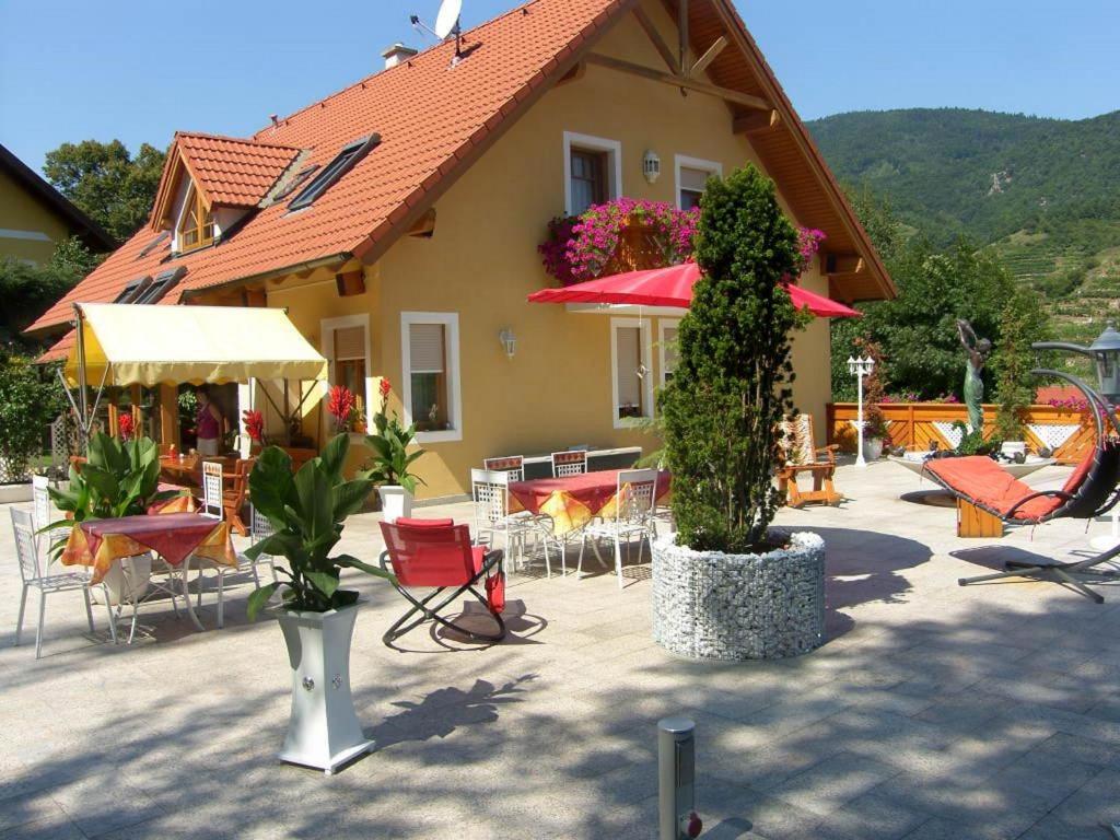 un patio con mesas y sillas y un edificio en Gästehaus zur schönen Aussicht, en Spitz