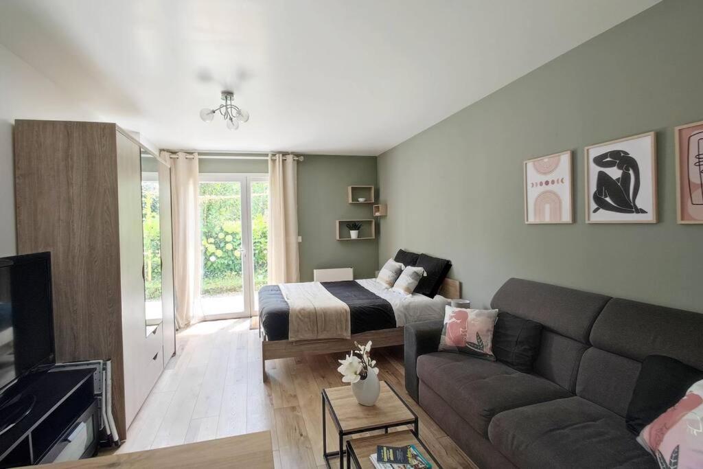 een woonkamer met een bed en een bank bij Les Treilles de Salies - Studio au calme in Salies-de-Béarn