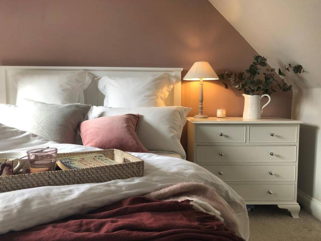 a bedroom with a bed with a dresser and a lamp at Idyllic cosy cottage close to Oxford and Le Manoir in Cuddesdon