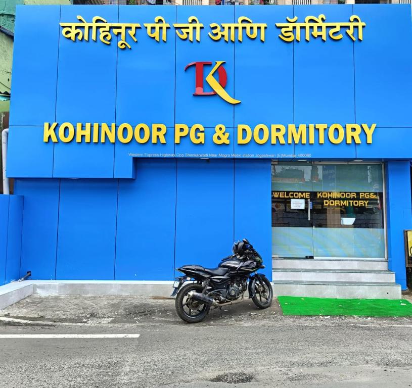 a motorcycle parked in front of a blue building at Kohinoor Dormitory in Mumbai