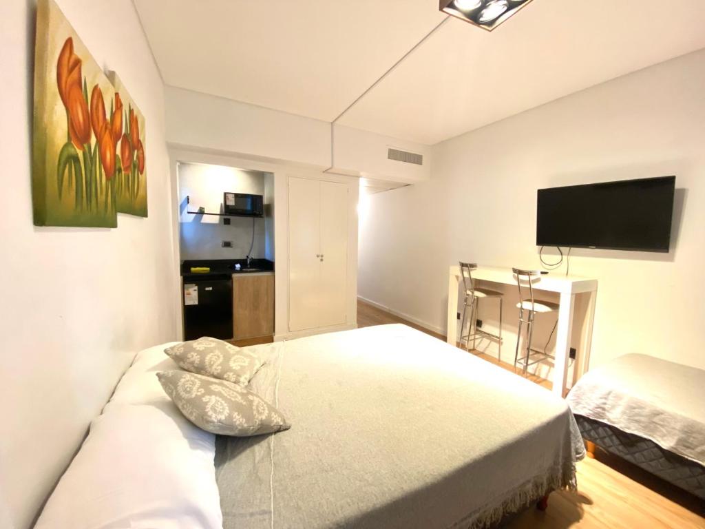 Apart hotel Ciudad de Bs As في بوينس آيرس: غرفة نوم بسرير وتلفزيون بشاشة مسطحة