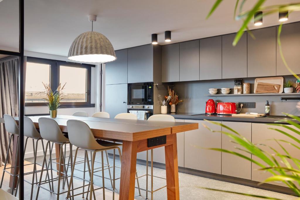 - une cuisine avec une table en bois et des chaises blanches dans l'établissement Aparthotel Adagio Paris Bercy Village, à Paris