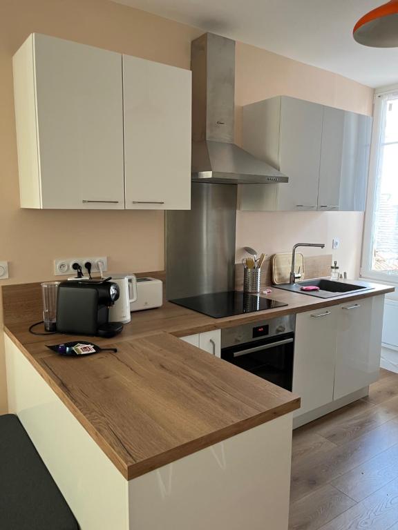 a kitchen with white cabinets and a wooden counter top at Clos Léonie - appartement 68m2 lumineux avec sauna in Givry