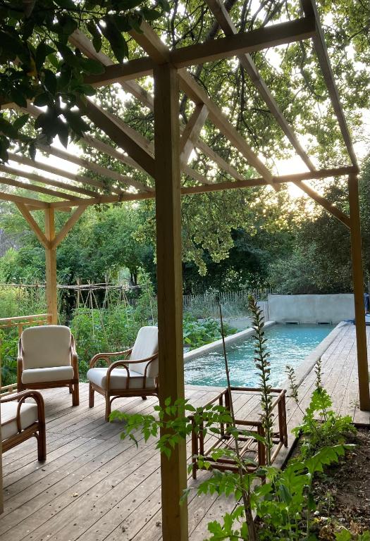 une terrasse en bois avec des chaises et une pergola à côté d'une piscine dans l'établissement Cabane de la leque, à Fontvieille