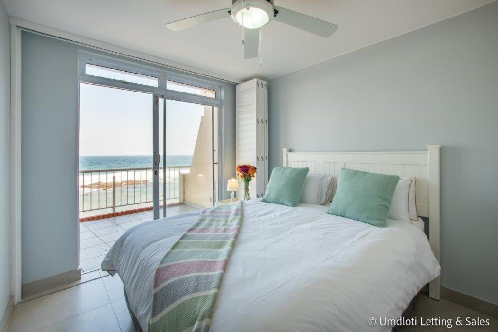 a bedroom with a bed with a view of the ocean at COZUMEL 213 in Umdloti
