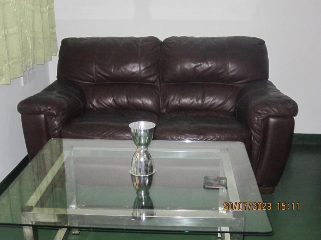 brązowa skórzana kanapa siedząca w salonie ze szklanym stołem w obiekcie My city Beds w mieście Kandy